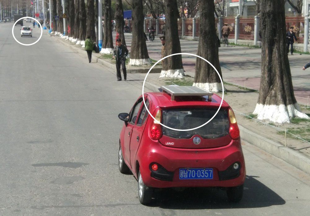 Chiếc xe đô thị loại nhỏ chạy trong công viên Pyongsong với tấm pin mặt trời trên nóc xe